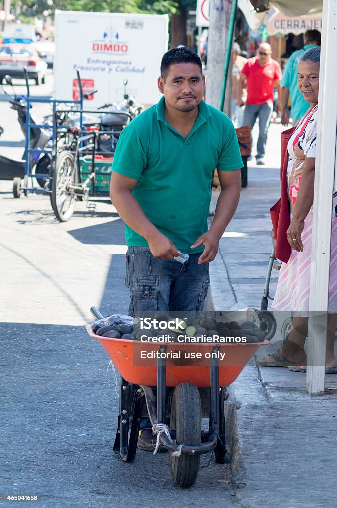 Man selling avocado in a wheelbarrow Huatulco Oaxaca, Mexico - February 27, 2015: The informal trade is a common practice in Mexico. People of all ages and genders come from their rural communities to sell their products on the streets. This man is offering avocados collected in his community. These products are normally cheaper than those bought at stablished stores. Mexican Culture Stock Photo