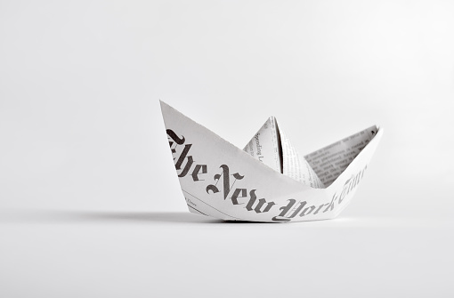 Kyiv, Ukraine - February 28, 2015: Paper boat of The New York Times newspaper on white background.