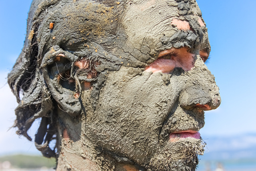 Man smeared with healing mud on beach