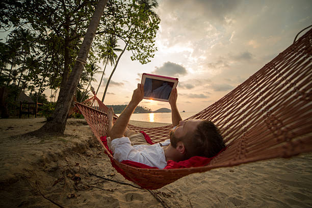 istock Young man on hammock with digital tablet-Tropical beach 465046394