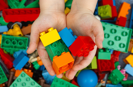 Tambov, Russian Federation - February 20, 2015: Lego Duplo Bricks in child's hands with Lego Duplo blocks background. Studio shot.