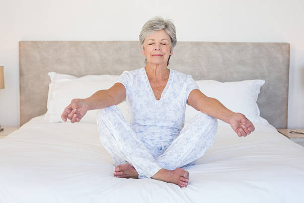 istock Senior woman meditating in bed 465049500