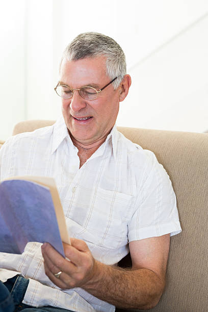 istock Senior man reading book at home 465050108
