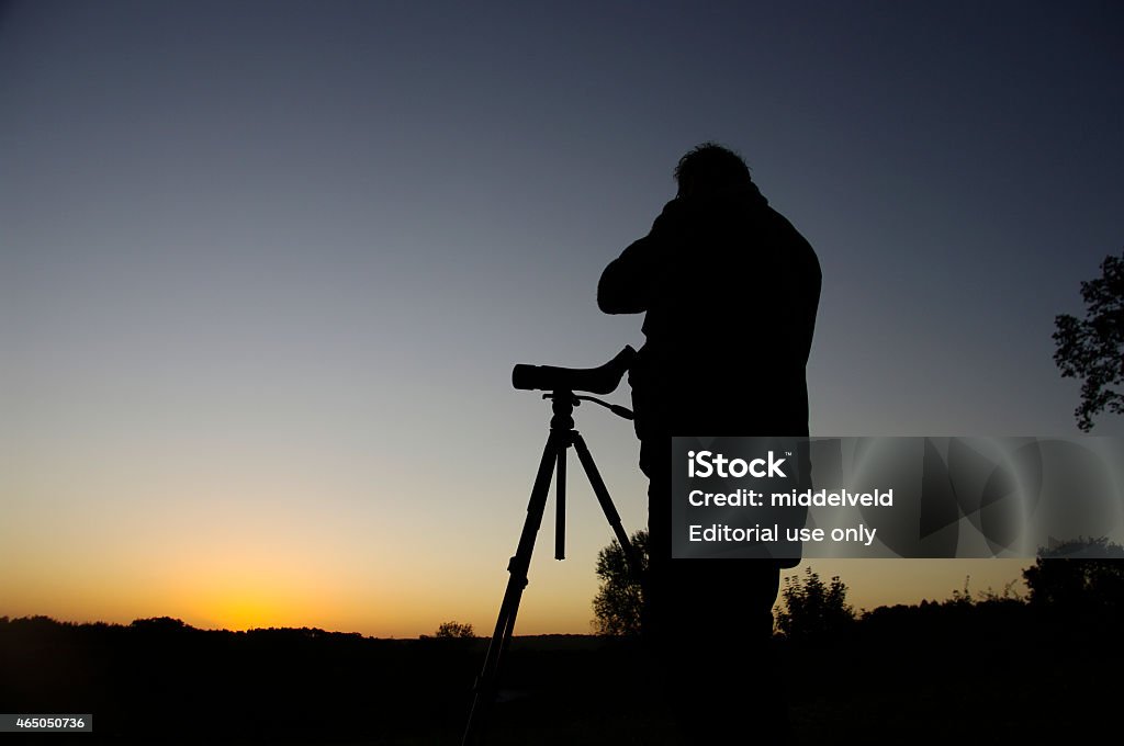 Bird watching in the morning Brunssum, the Netherlands- September 14, 2011: Daybreak scene where a man is bird watching during an impressive sunrise early in the morning. He is waiting for the birds in this beautiful heathland area. 2015 Stock Photo