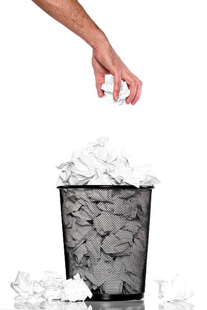 istock Hand dropping crumpled paper into an overflowing trash can 465051041
