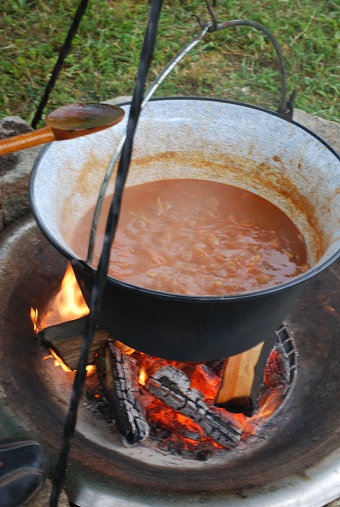 Cooking pot with goulash at the campfire