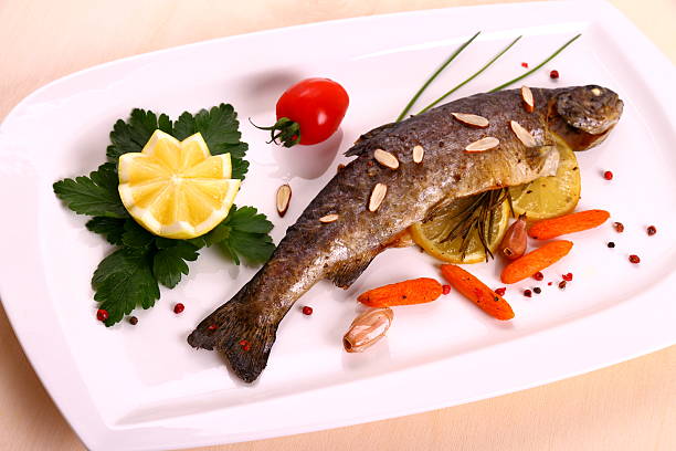 istock Fried trout with lemon and split almonds on white plate 465056911