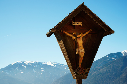 crucified Jesus Christ statue and mountain range in the alps