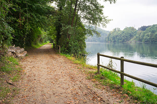 Path along the Adda river banks. Color photo View of a trekking path under the woods, along the Adda river banks, Lombardy (Northern Italy), at the border between the Province of Monza/Brianza and Bergamo. strada sterrata stock pictures, royalty-free photos & images