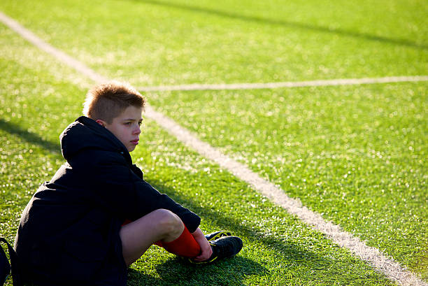 小さなサッカー選手 expelled 悲しげなシッティングエリアを引き受け - soccer guilt soccer player sitting ストックフォトと画像