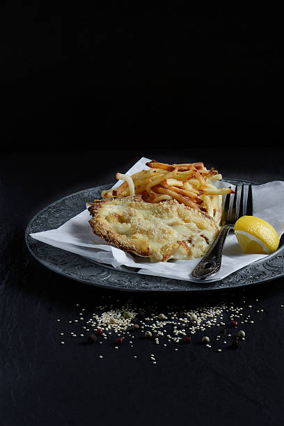 Scallops Classic Coquilles St. Jacques plated and styled with skinny fries and lemon garnish against a black background. Copy space. seafood gratin stock pictures, royalty-free photos & images