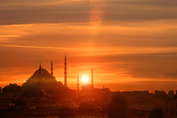 Sunset at Istanbul, with sun behind silhouette of Blue Mosque Beautiful sunset at Istanbul, Turkey, with sun setting behind the silhouette of Blue Mosque, showing the profile of the dome and minarets. Red and orange cloudscape fills the scene with warm light creating a dramatic sky. golden horn istanbul photos stock pictures, royalty-free photos & images