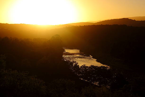 sunset in the mountains sunset from the top of a mountain with a natural river in the middle of the scene tarde stock pictures, royalty-free photos & images