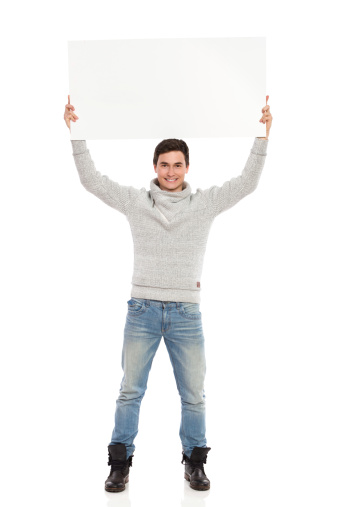 Smiling young man holding banner over his head. Full length studio shot isolated on white.