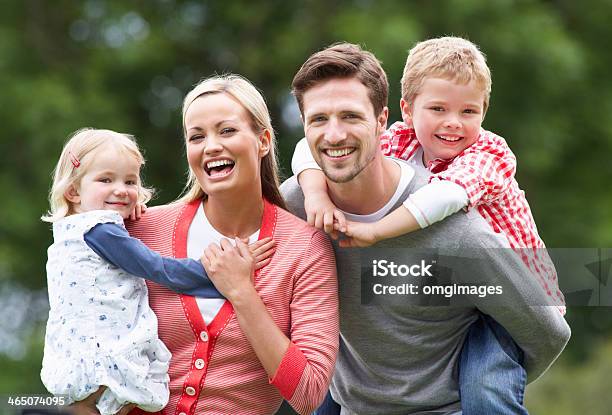 Parents Giving Children Piggybacks In Countryside Stock Photo - Download Image Now - 20-29 Years, 6-7 Years, 8-9 Years