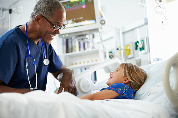 macho enfermeira falar com criança na cama do hospital - male nurse black nurse doctor imagens e fotografias de stock