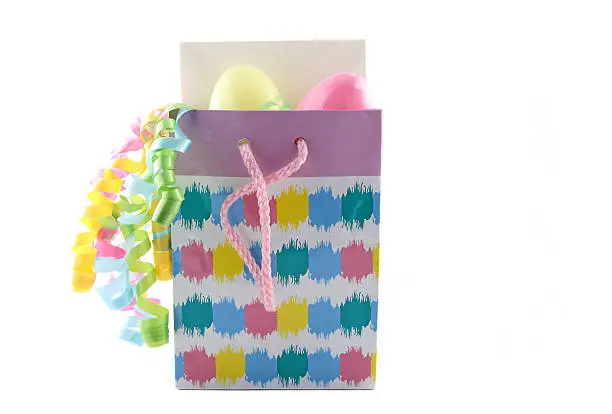 Easter gift bag with card, eggs, and ribbon isolated on a white background.