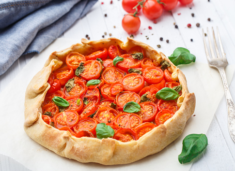 Cherry tomato tart with basil on a parchment paper