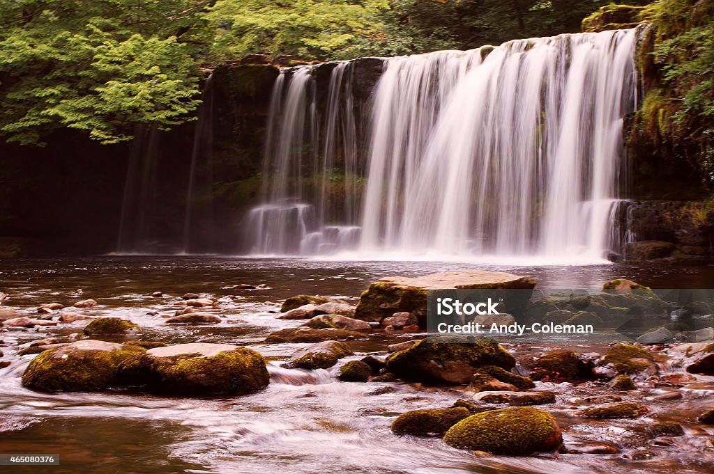 Sgwd Ddwli Uchaf Waterfall within the Brecon Beacons National Park Sgwd Ddwli Uchaf Waterfall in the Brecon Beacons National Park, South Wales. I captured this picture using a longish exposure, so as to slightly blur the water, thus giving a feel of fluid mobility. There are stepping stone type rocks in the foreground, with the large and wide waterfall in the background. 2015 Stock Photo