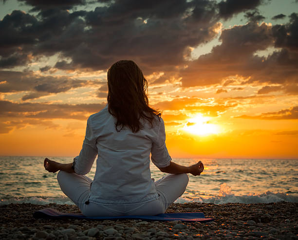 istock Woman Practicing Yoga by the Sea at Sunset 465082724