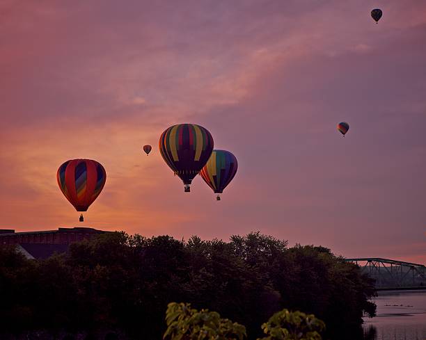 Sunrise Launch Hot air ballon launch at sunrise. Urban setting, some trees along river's edge. Sky is beginning to show color. ballooning festival stock pictures, royalty-free photos & images