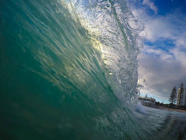 istock Green wave breaking on the beach against a blue sky 465087240