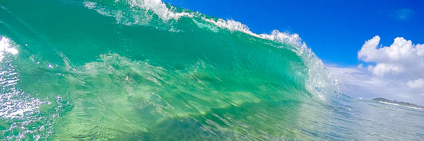 istock Green wave breaking on the beach against a blue sky 465088660