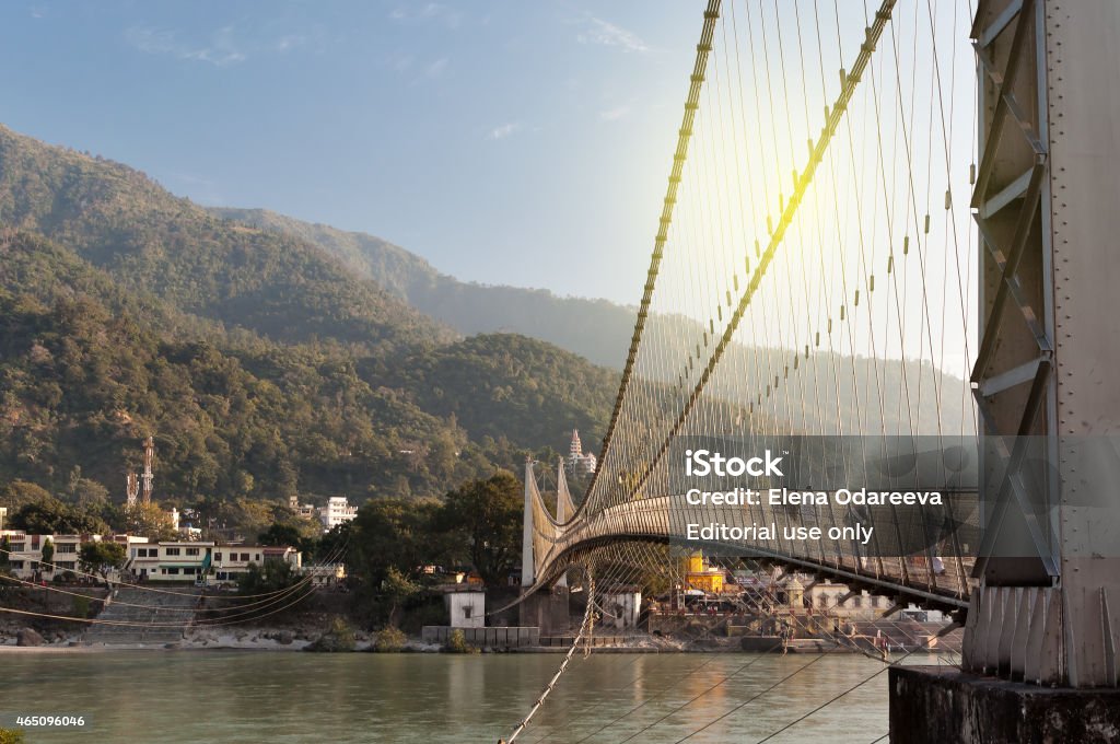 View of River Ganga and Ram Jhula bridge Rishikesh, India - December 11, 2014: View of River Ganga and Ram Jhula bridge. Rishikesh is  World Capital of Yoga,  has numerous yoga centres that also attract tourists 2015 Stock Photo