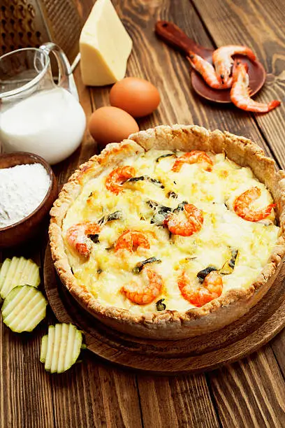 Quiche with shrimp and zucchini on a wooden table