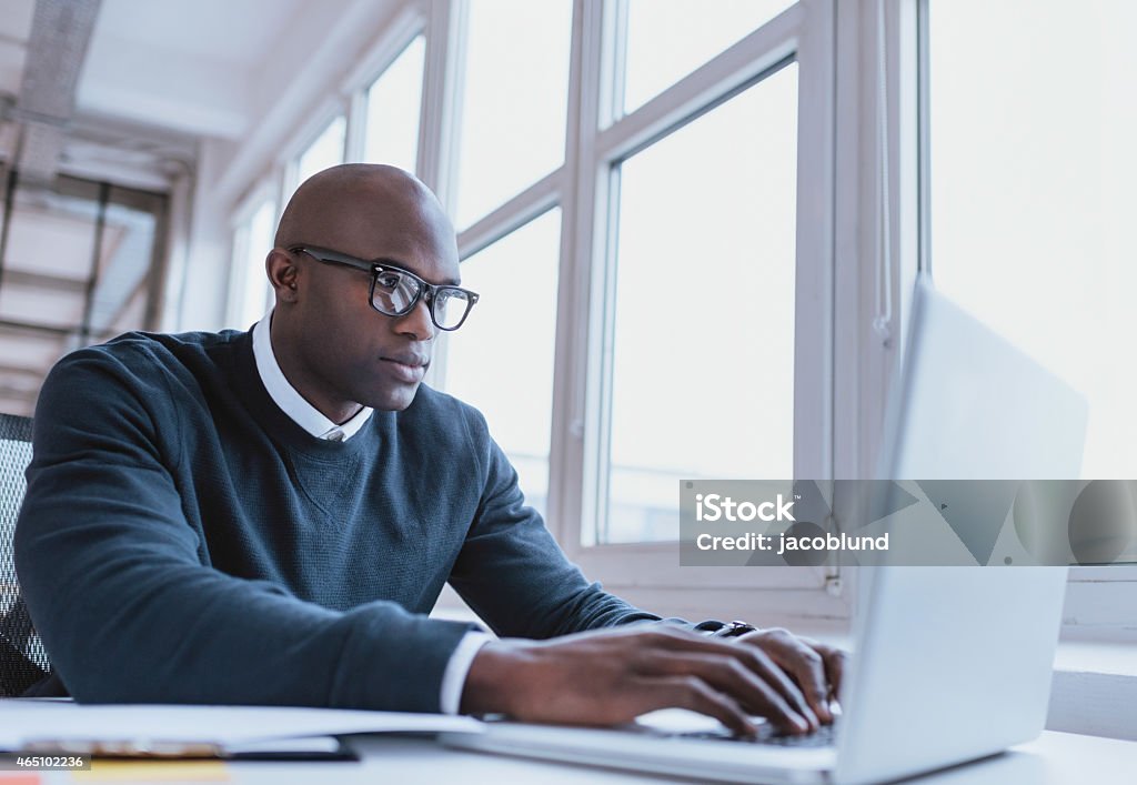 African american businessman working on his laptop Image of african american businessman working on his laptop. Handsome young man at his desk. People Stock Photo