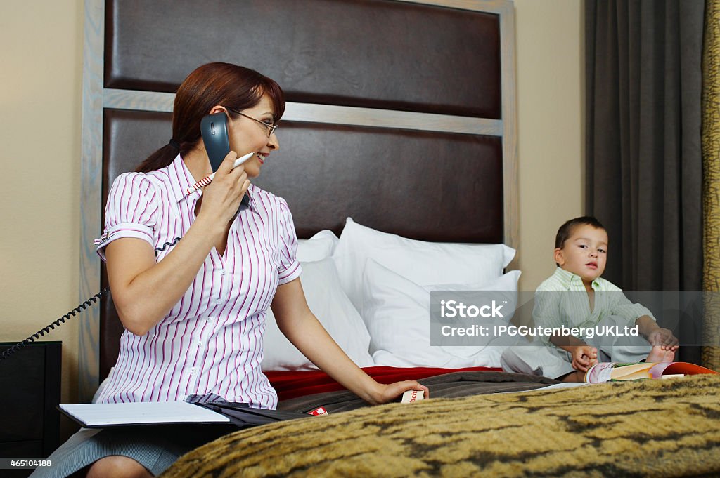 Businessperson Business woman using phone with son on bed 2-3 Years Stock Photo