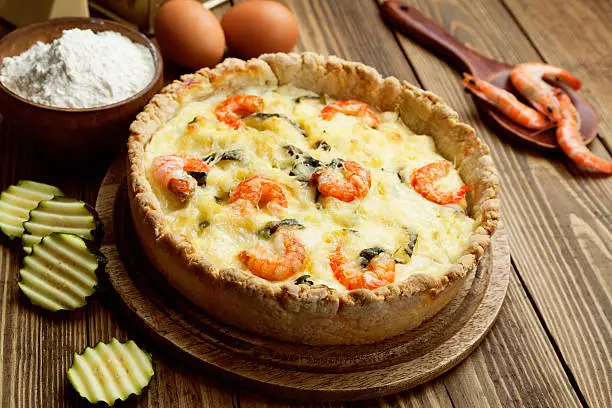 Quiche with shrimp and zucchini on a wooden table