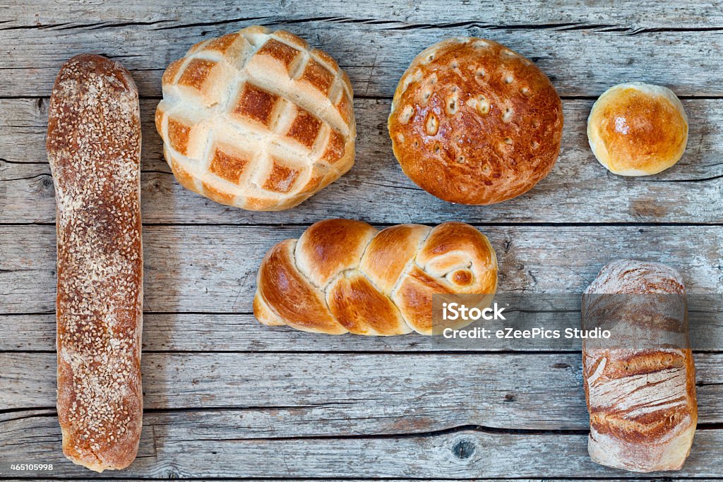 Various Bread Types On Wood Background Overhead shot of various types of bread on wood background. 2015 Stock Photo