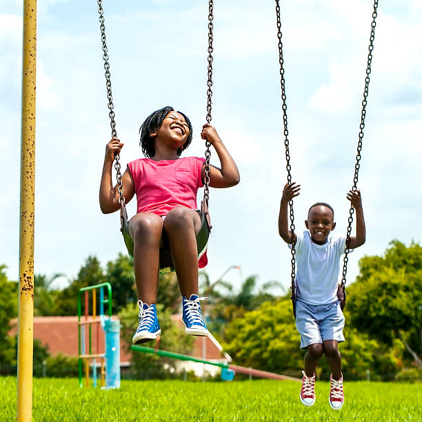 afrykańskie dzieci zabawa huśtać się w parku. - child swinging playground african descent zdjęcia i obrazy z banku zdjęć