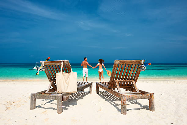 istock Two chairs on the beach with a couple running into the ocean 465110332