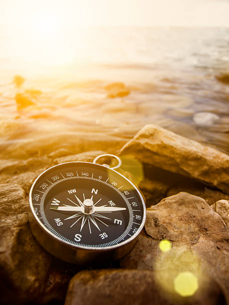 compass on the shore at sunrise stock photo