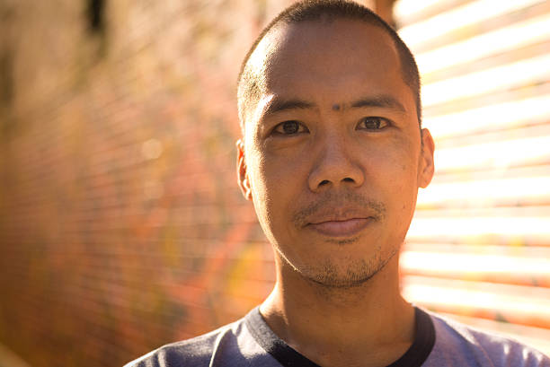 istock Asian male standing against graffiti wall 465116465