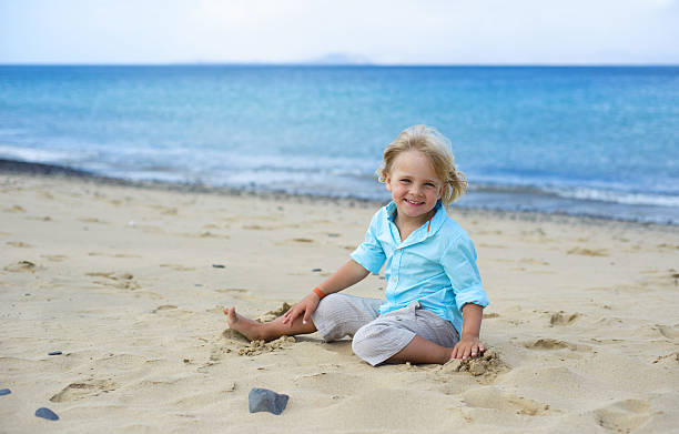 istock Cute little smiling boy plays on the beach 465118094