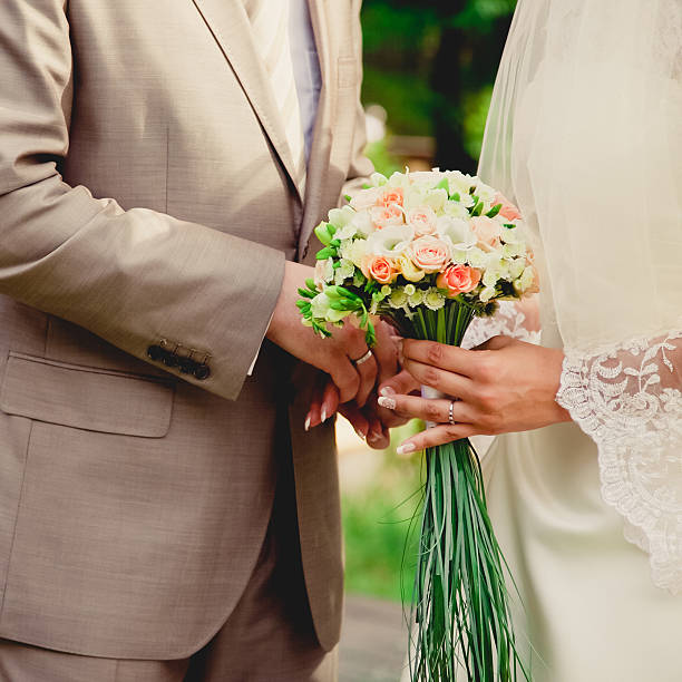 istock mans hand putting a wedding ring on the brides finger 465118462