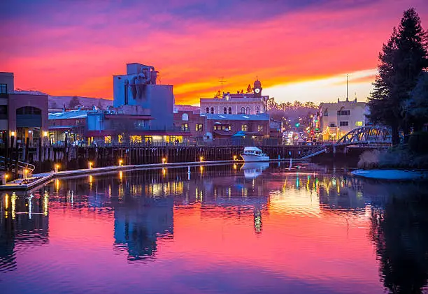 A brilliant winter sunset is reflected in the Petaluma River turning basin in front of the historic downtown Petaluma, CA, waterfront.