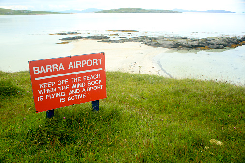 A red sign for the Barra Airport which uses the beach for runways. This was taken at high tide and the runways are covered. 