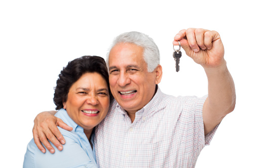 Portrait of smiling senior couple with house key isolated over white