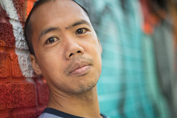 istock Asian male standing against graffiti wall 465129109