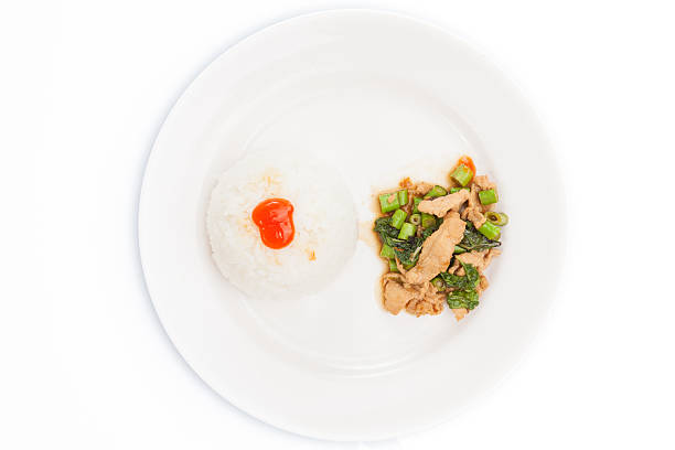Thai food, kapao moo,  pork with basil, minced pork fried with chilli pepper and sweet basil. Close-up with shallow depth of field. angle/top view on white plate set