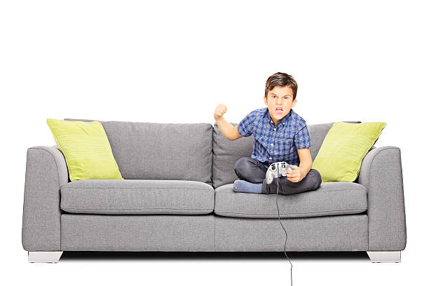 istock Nervous kid sitting on sofa and playing video games 465129735