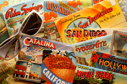 San Diego, California, USA - November 8, 2013: A pair of white Foster Grant sunglasses on top of a group of vintage postcards showing various California tourist destinations. Shot in a studio setting.