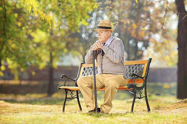 istock Sad senior man with cane sitting in park 465136543