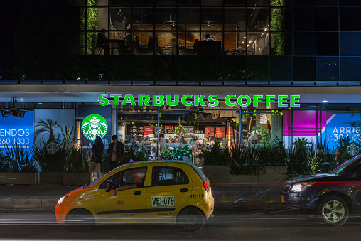 Bogota, Colombia - December 26, 2014: Starbucks Coffee Shop on Calle 93A opposite the Parque de la 93, in the capital city of Bogota, in Colombia, South America.  Photo shot at night with delayed shutter release of 4 seconds. People can be seen both inside and outside the restaurant. Horizontal format; people.  Camera: Cannon EOS 5D MII; Lens Canon EF 24-70 f2.8L USM.