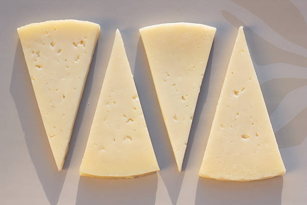 Manchego cheese. Four slices of semi matured manchego cheese. machego stock pictures, royalty-free photos & images