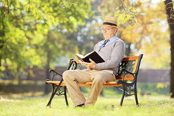 istock Senior man with hat sitting on bench and reading 465139977